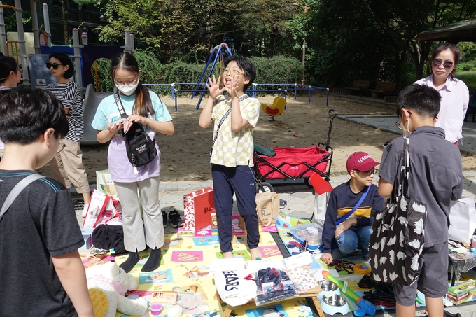꼬마 사장님이 자신의 물건이 세일중이라고 외치고있다.